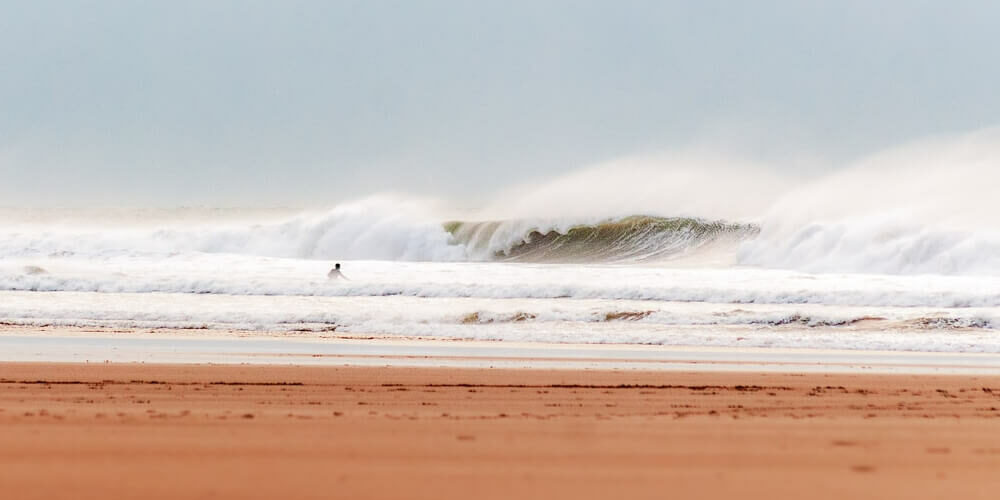 surfer entering a windy sea in north devon with large offshore waves