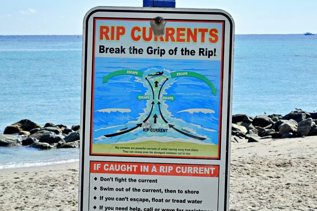 a sign warning about the dangers of surfing and rip currents