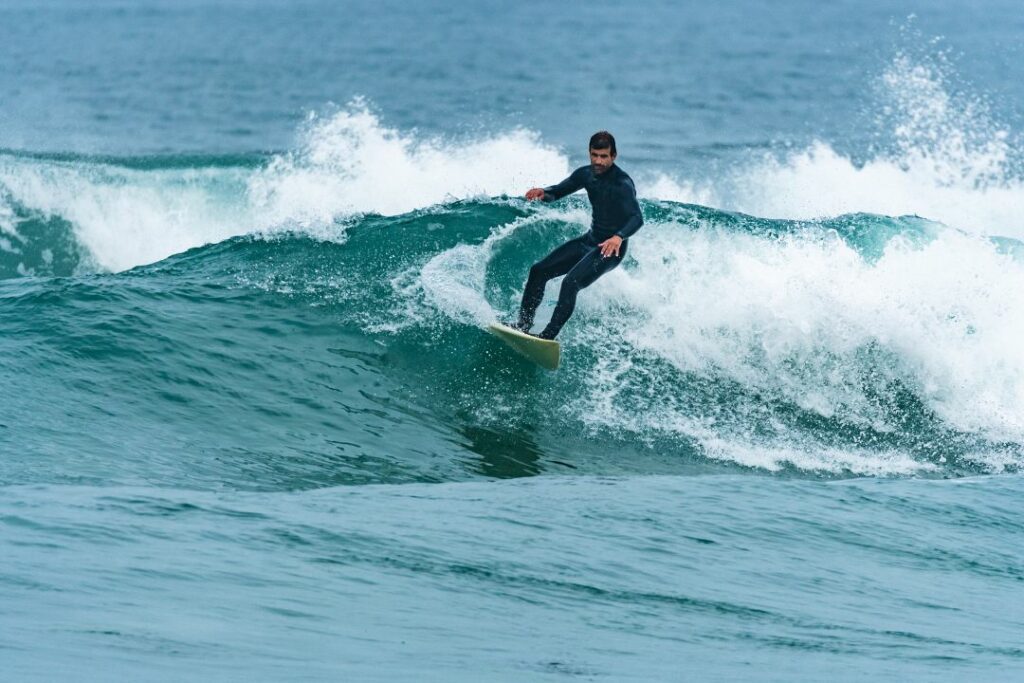 surfer in a 3mm wetsuit and boots on a chest high wave